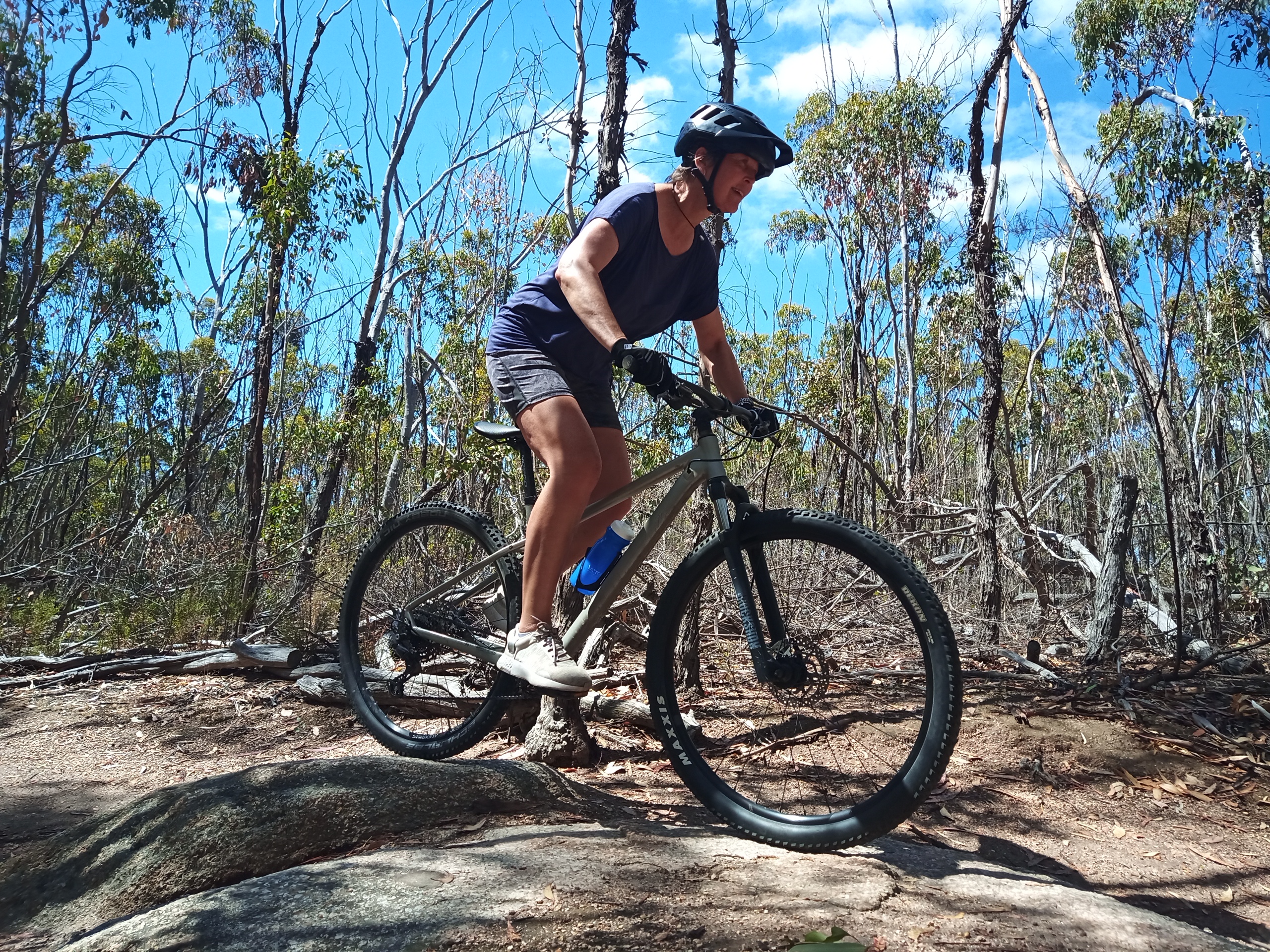 New female rider successfully tackles a small rock feature on a sunny day at the You Yangs